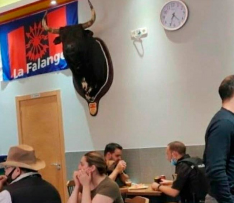 Agentes de la policía disfrutando de un café bajo el "patriótico" escudo de La Falange y una celtibérica cabeza de toro